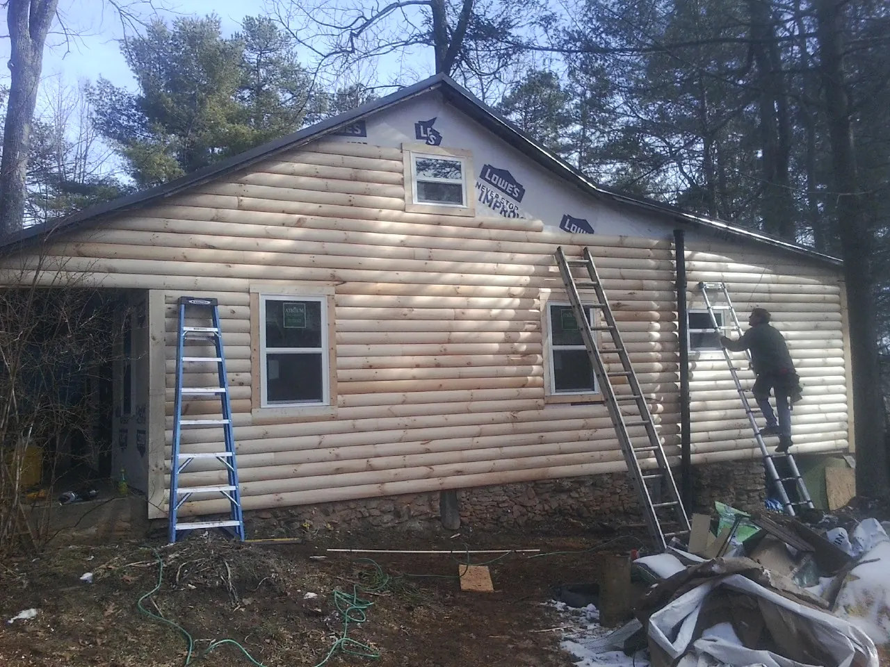 Ladders set against fresh log siding during an exterior remodel in Lee Center