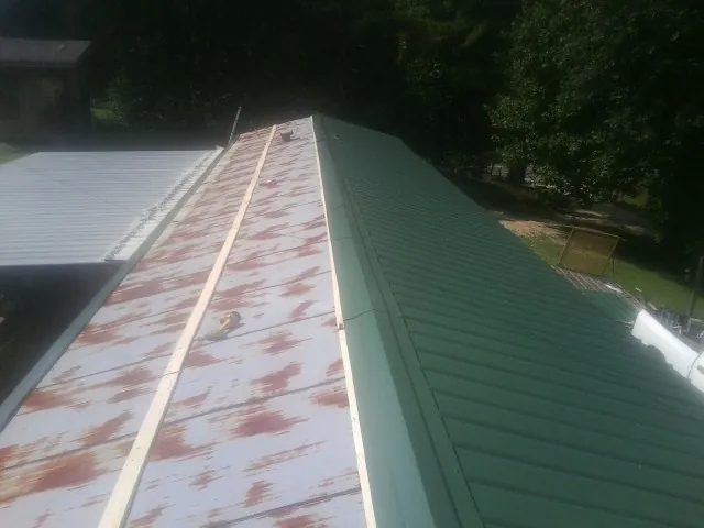 Old rusted panels beside newly installed green metal roofing — Wind Damage Roof Repair by Roofing Brothers in Lee Center