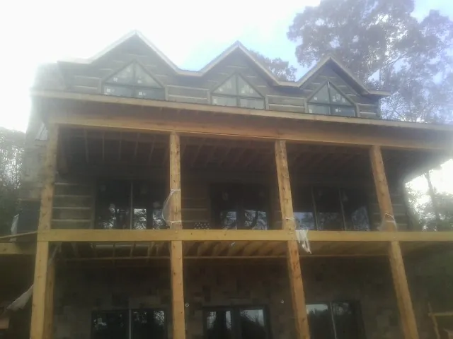 Dormers and porch framing on a large log home under construction — Roof Coating work by our crew in Lee Center